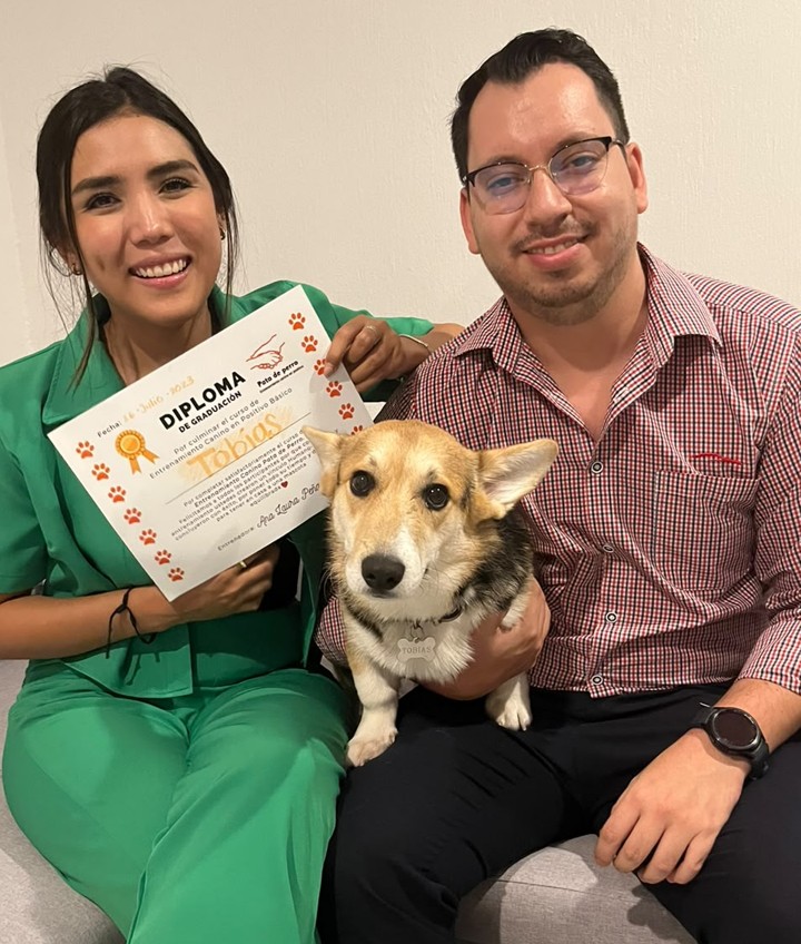 Corgi con sus dueños y su diploma de graduación